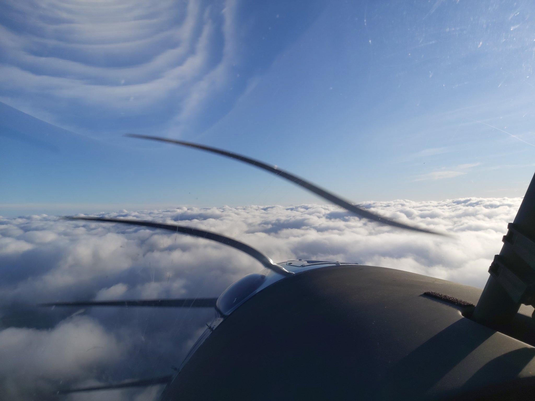 Blick aus dem Cockpit eines Kleinflugzeugs über einer Wolkendecke